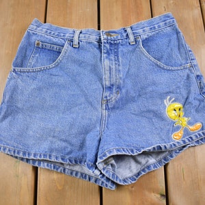 May include: Blue denim shorts with a yellow Tweety Bird cartoon character embroidered on the right leg.