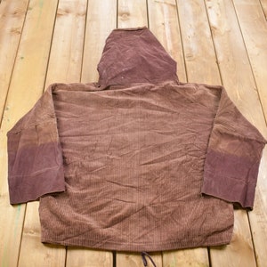 May include: A brown corduroy hoodie with a drawstring. The hoodie has a brown hood and long sleeves.