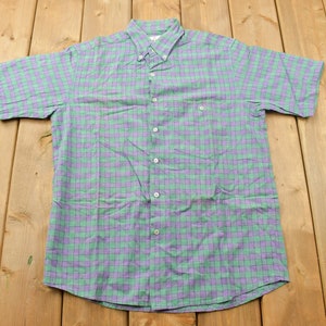 May include: A green and purple checked short-sleeved button-down shirt.
