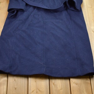 Pu&ograve; includere: Una vestaglia blu navy con cintura.