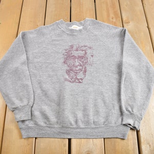 Puede incluir: Una sudadera gris con una impresión de estilo vintage de la cara de Albert Einstein en marrón.