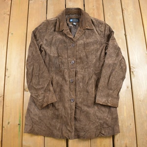 May include: A brown suede jacket with a button-up front and long sleeves. The jacket has a collar and a slightly fitted silhouette.