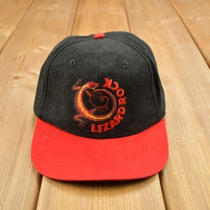 Könnte beinhalten: Schwarze und rote Baseballkappe mit einem gestickten Logo eines Leguan mit dem Text "Lizard Pro" in einem Kreis.