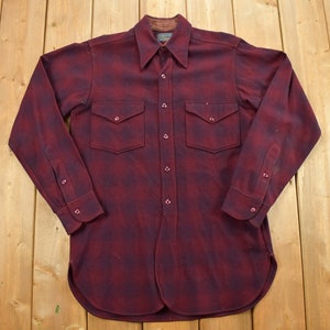 May include: A long-sleeved, red and black plaid flannel shirt with a button-down collar and two chest pockets.