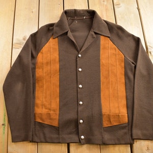 May include: A brown long-sleeved shirt with a suede panel on the front and back. The shirt has a button-up front and a collar.