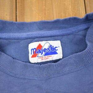May include: A blue t-shirt with a white tag that says "Majestic" in blue letters. The tag also says "Made in China RN 53857".