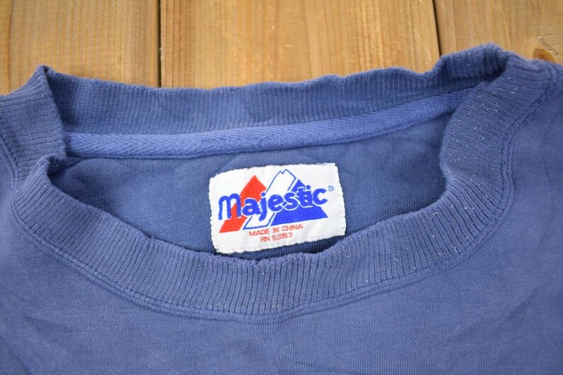 May include: A blue t-shirt with a white tag that says "Majestic" in blue letters. The tag also says "Made in China RN 53857".
