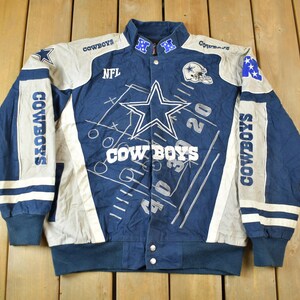 May include: A blue and white baseball jacket with the Dallas Cowboys logo and team name. The jacket has a zipper closure and a snap button collar.