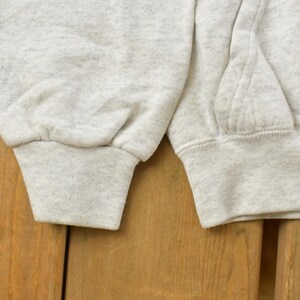 Op de afbeelding: Een lichtgrijs gem&ecirc;leerd sweatshirt met lange mouwen en geribbelde boorden. Het kledingstuk heeft een gestructureerd, gespikkeld stofpatroon over het geheel, met zichtbare stikdetails langs de mouwnaden en een deel van de voorzak.