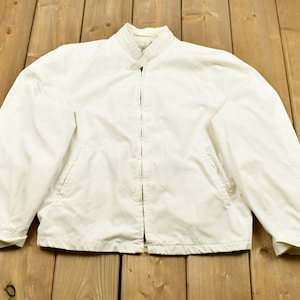 May include: A white zip-up jacket with a stand-up collar.