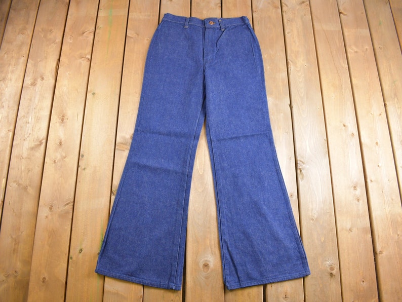 Op de afbeelding: Een paar blauwe denim bellbottom broek met een hoge taille en een knoopsluiting.