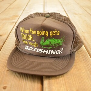 May include: Brown and tan trucker hat with the text "When the going gets TOUGH... the tough GO FISHING!" A green fish graphic is also on the front. The hat has a mesh back and a curved brim.