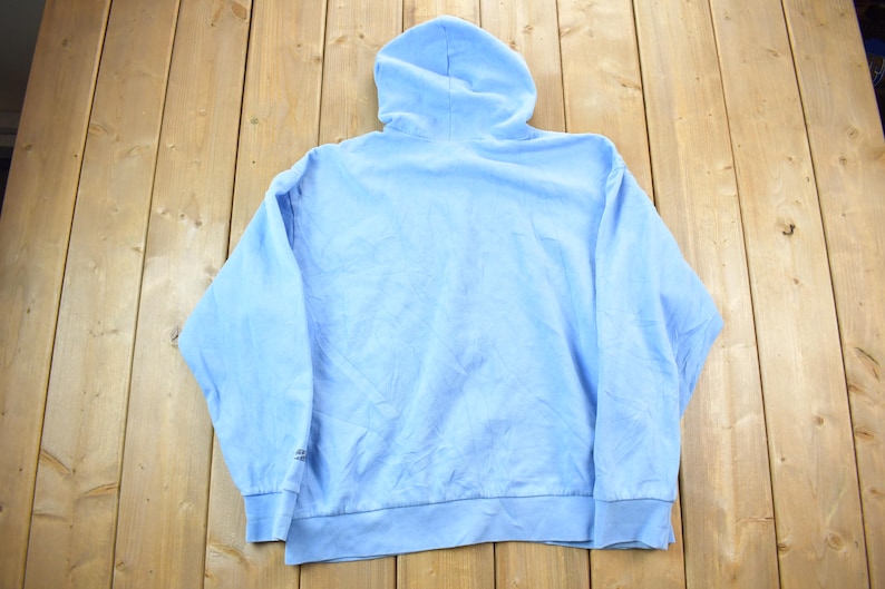 May include: A light blue hooded sweatshirt with long sleeves. The sweatshirt is made of a soft, comfortable fabric.