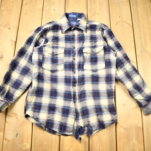 May include: A blue, yellow, and white plaid flannel shirt with long sleeves and a button-up front.