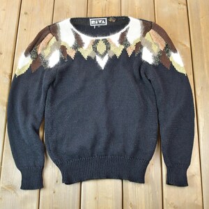 May include: Black sweater with a brown, white, and gold geometric pattern around the neckline. The sweater has long sleeves and a crew neck.