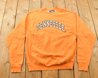 May include: Orange sweatshirt with a white arch design that reads "TENNESSEE".