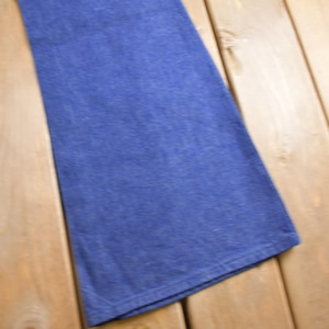 Op de afbeelding: Een paar blauwe denim jeans met een wijde pijp, gevouwen en plat gelegd op een houten oppervlak.