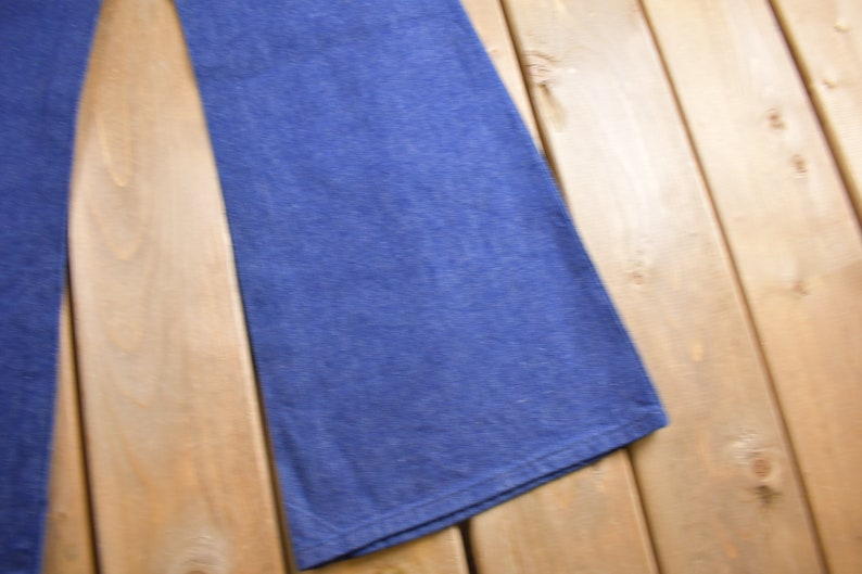 Op de afbeelding: Een paar blauwe denim jeans met een wijde pijp, gevouwen en plat gelegd op een houten oppervlak.