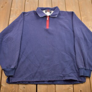 May include: A navy blue long-sleeved sweatshirt with a red zipper and the word "SCAMP" on the collar.