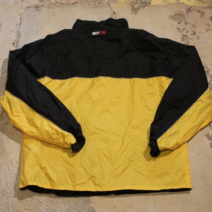 Pu&ograve; includere: Una giacca a vento nera e gialla con chiusura a zip. La giacca ha un bordo blu intorno alle maniche e al collo.