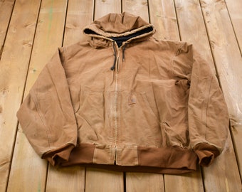 May include: A brown hooded work jacket with a zipper closure and a Carhartt logo patch on the chest.