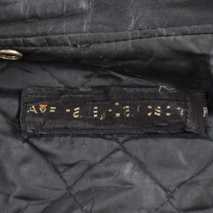 Puede incluir: Primer plano del forro de una chaqueta de cuero negra con una etiqueta negra que dice "AV = -2. = -2. 55CT".