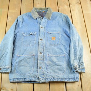 May include: Light blue denim work jacket with a corduroy collar. The jacket has four front pockets, a button-up closure, and a small logo patch on the chest. A classic, durable outerwear piece.