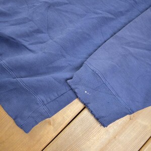 May include: A blue sweatshirt with a frayed edge on the sleeve.