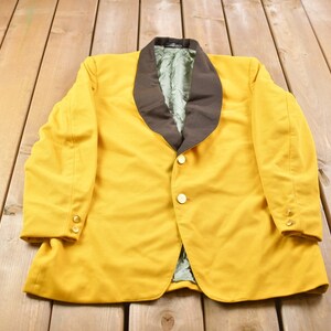 Könnte beinhalten: Ein gelber Blazer mit braunem Kragen und goldenen Knöpfen.
