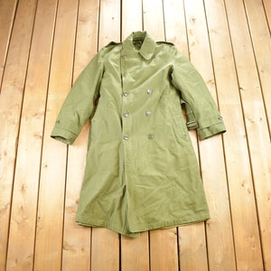 May include: A long, green, double-breasted trench coat with a belt. The coat is made of a thick, durable fabric and has a classic design.