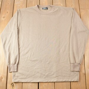 May include: A long-sleeved, beige t-shirt with a crew neck. The shirt is made of a soft, comfortable fabric and has a relaxed fit.