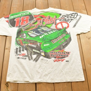 May include: White t-shirt with a green and red print of a racing car with the number 18 and the text "Interstate Batteries" and "Speed Limit".
