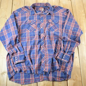 Op de afbeelding: Blauw en rood geruit overhemd. Dit shirt met lange mouwen heeft een klassiek ruitpatroon in blauw en rood. Het heeft een kraag, manchetten met knopen en twee borstzakken. Het shirt is gemaakt van een zacht materiaal, waarschijnlijk katoen.
