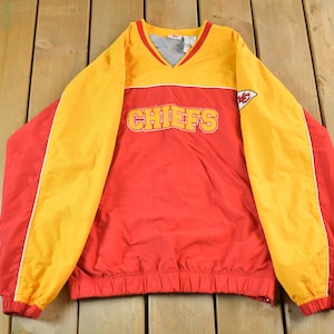 May include: A red and yellow Chiefs pullover jacket. The jacket has yellow sleeves and a yellow upper chest area. The word "CHIEFS" is across the chest in yellow lettering. A Chiefs logo is on the right chest.