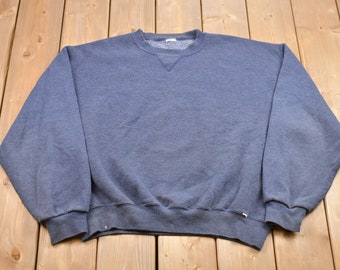 May include: A plain blue sweatshirt with a crew neck.