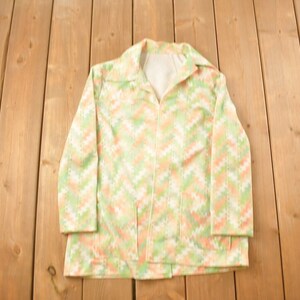 May include: A white, green and peach patterned jacket with a zip closure. The jacket has a collar and long sleeves.