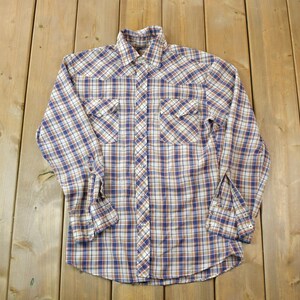 May include: A long-sleeved plaid shirt with a button-down collar. The shirt is white with blue and orange plaid.