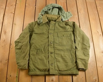 May include: A green hooded jacket with a button closure and a large pocket on the front.