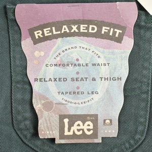 May include: A close-up of a dark green pair of jeans with a white tag that reads "Relaxed Fit" and "The brand that fits." The tag also includes the Lee logo and the text "Comfortable Waist", "Relaxed Seat & Thigh", "Tapered Leg", and "1-800-4-LEE-FIT".
