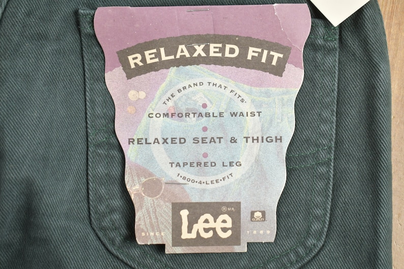 May include: A close-up of a dark green pair of jeans with a white tag that reads "Relaxed Fit" and "The brand that fits." The tag also includes the Lee logo and the text "Comfortable Waist", "Relaxed Seat & Thigh", "Tapered Leg", and "1-800-4-LEE-FIT".