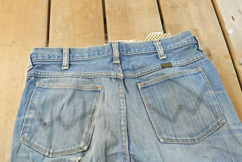 Puede incluir: Vaqueros de mezclilla azul claro con los bolsillos traseros visibles. Los vaqueros tienen un dise&ntilde;o cl&aacute;sico con el logotipo de Wrangler en el bolsillo trasero. Los vaqueros est&aacute;n hechos de un material de mezclilla duradero.