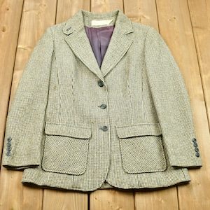 May include: A brown and beige tweed blazer with a button closure and two flap pockets. The blazer has a checkered pattern.