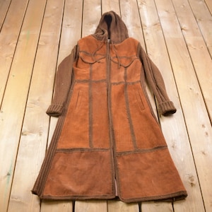 May include: A brown suede and knit hooded jacket with a zipper closure. The jacket has a patchwork design and is made of a soft, comfortable material.