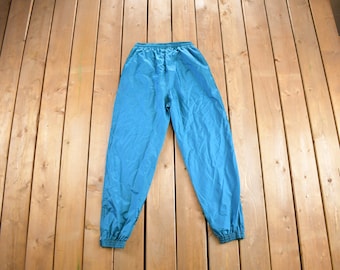 Könnte beinhalten: Tealblaue Nylon-Trainingshose mit elastischem Bund und Kordelzug.