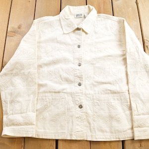 May include: A white long-sleeved button-up shirt with a geometric pattern. The shirt has a collar and a button closure. The brand name "CHIC" is visible on the label.