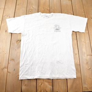 May include: White t-shirt with a black and white graphic of a cartoon character with the text "The Original 1992" printed on the front.