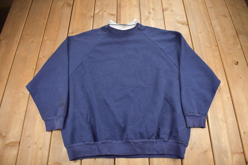 May include: A navy blue sweatshirt with a white ribbed collar.