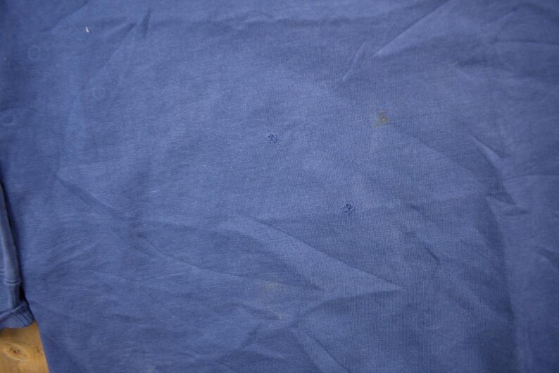 May include: A plain blue t-shirt with a few small holes.