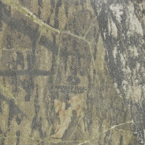 May include: Close-up of a camouflage pattern fabric. The design features a blend of brown, green, and gray hues, creating a textured, naturalistic appearance. The fabric has a subtle, mottled effect, with the "Mossy Oak" logo visible.