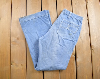 May include: A pair of light blue denim jeans with a wide leg and a high waist. The jeans have a single back pocket with a flap.
